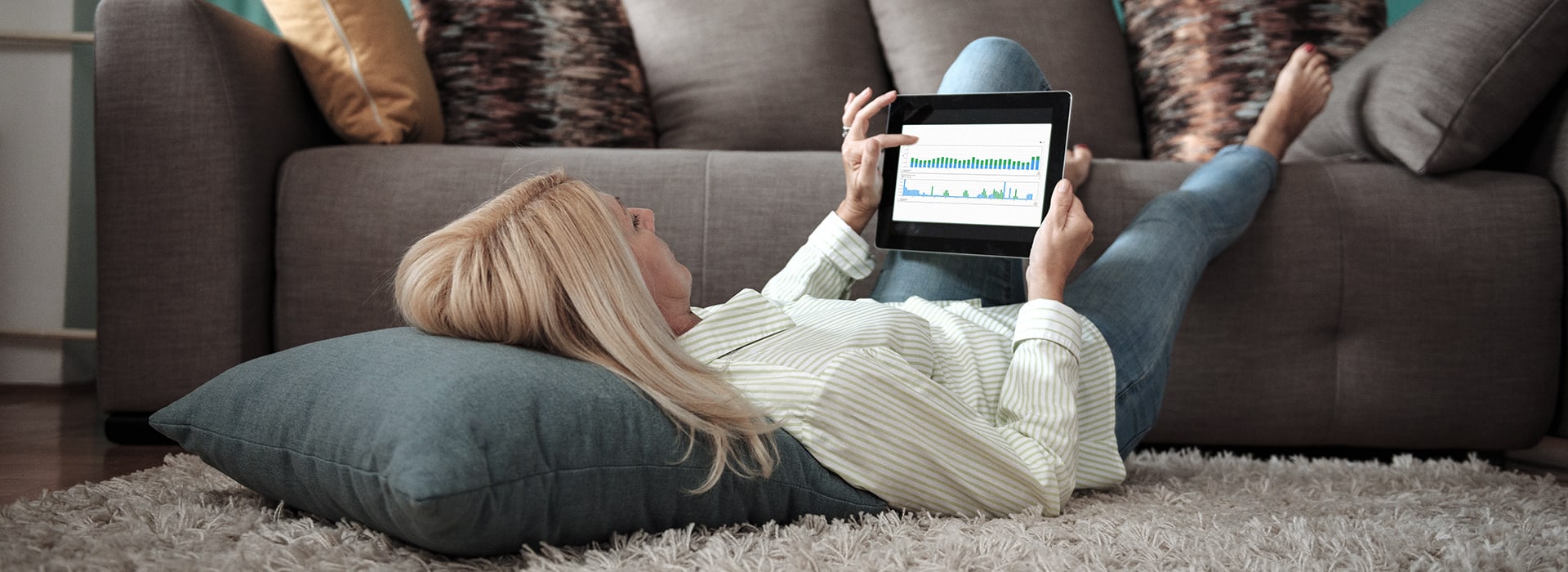 Woman lying in front of a sofa with a tablet