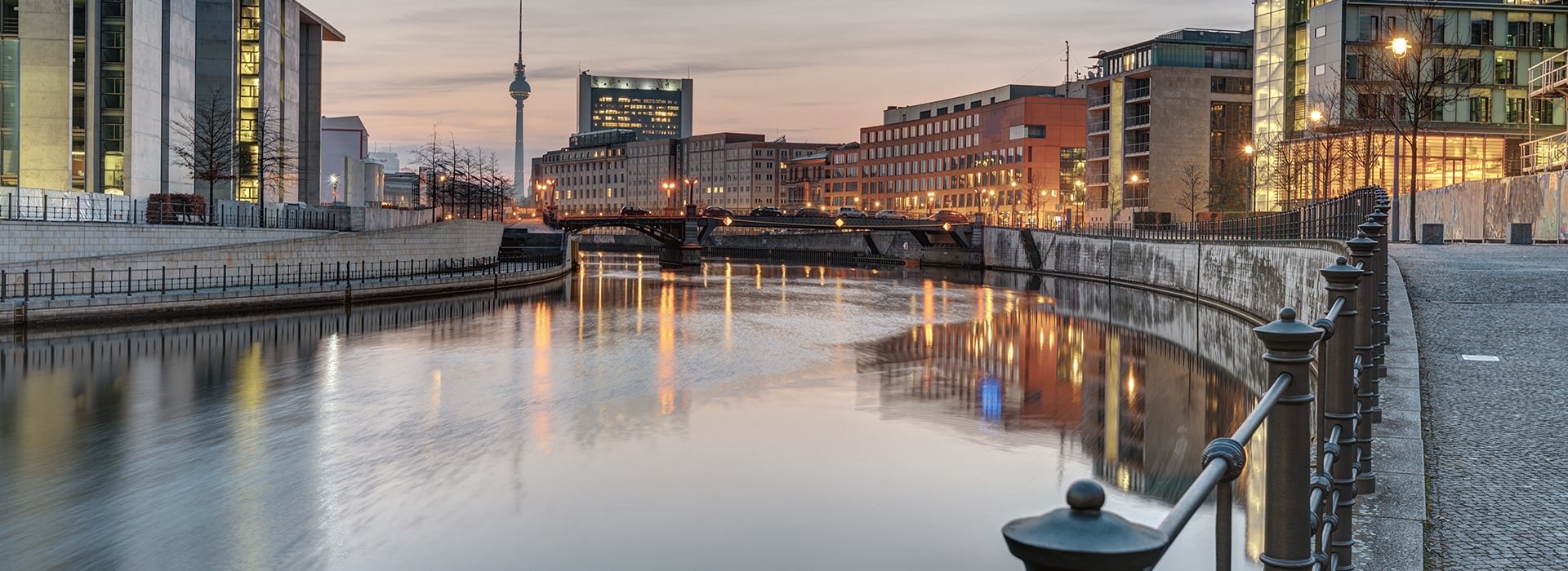 a river runs through a city, houses and a street in an evening atmosphere