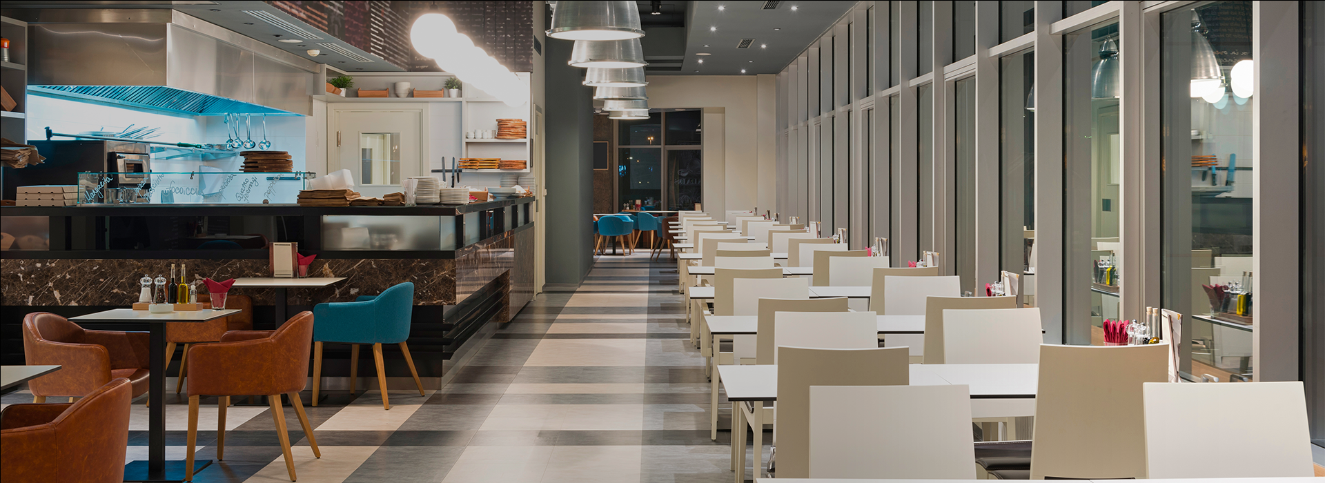 A canteen with a food counter and tables with colourful chairs