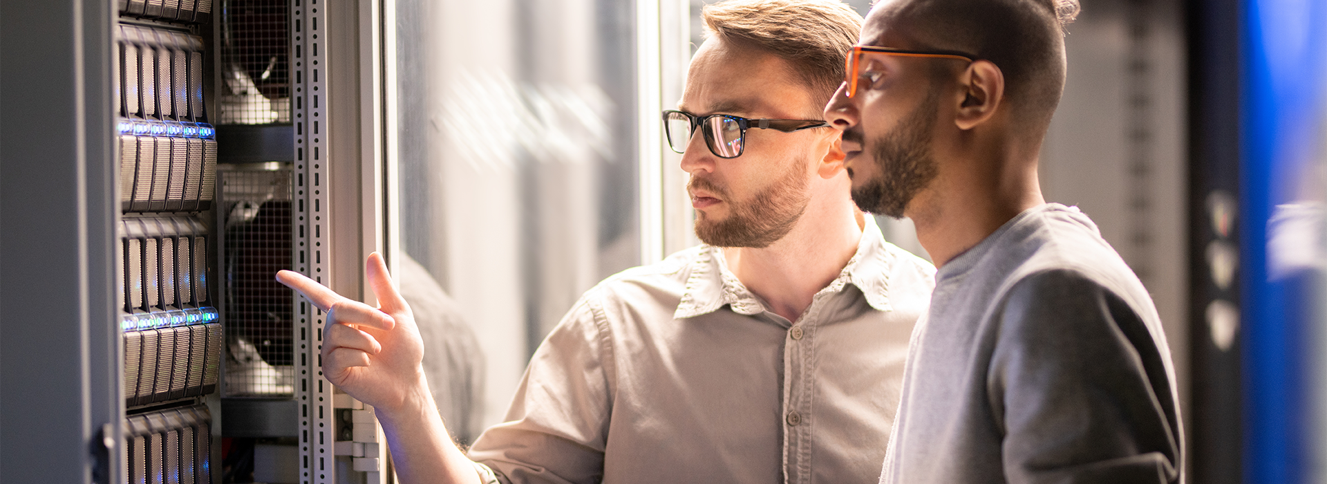 Two men look at a server in a data center.